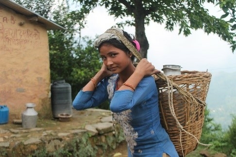 A young Nepali woman carrying a heavy water jug on her back/head