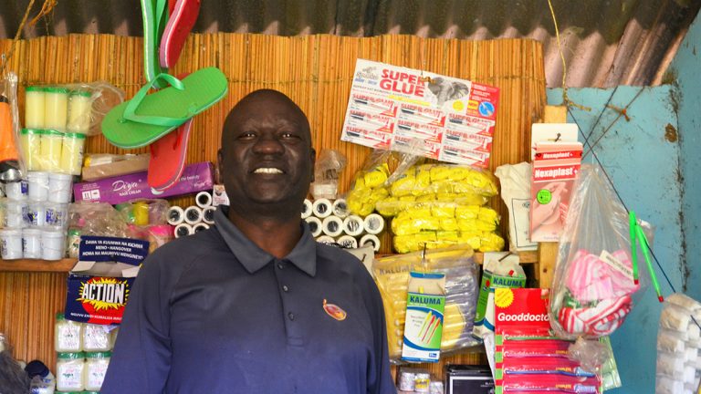 Pascal smiling in front of his store with various products on display behind him